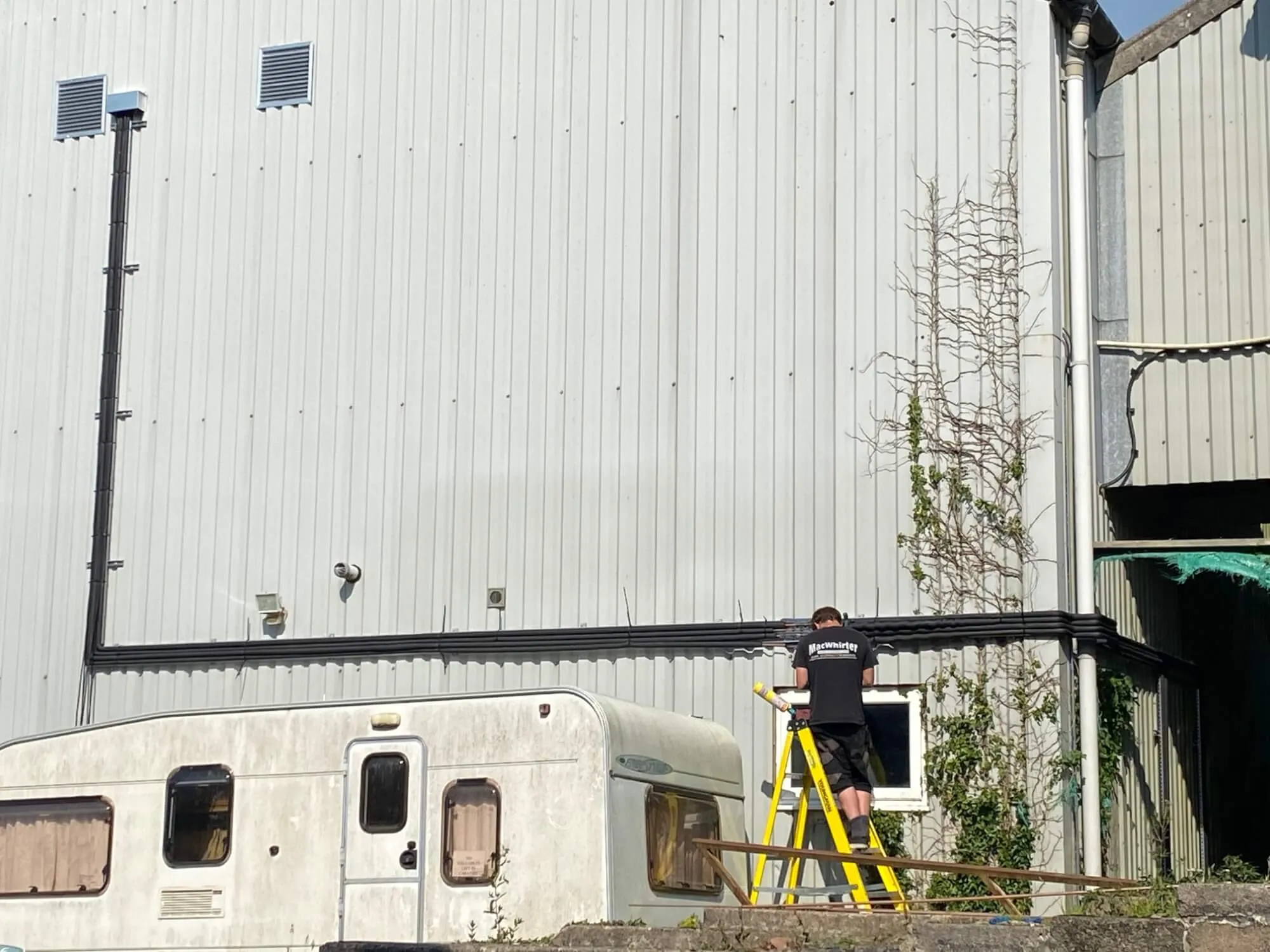 A man standing on a ladder next to a building.