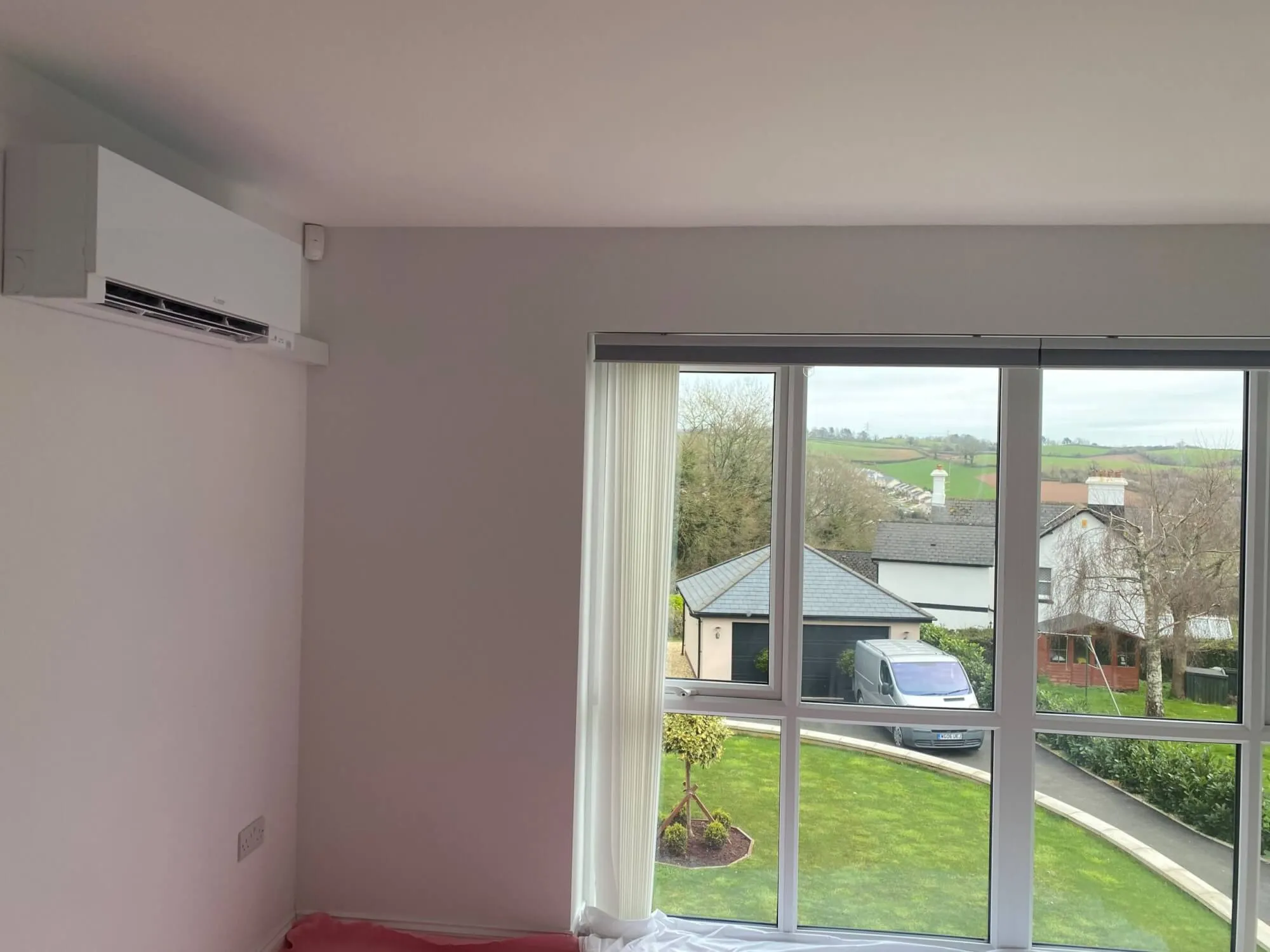 A bedroom with a bed and a large window.