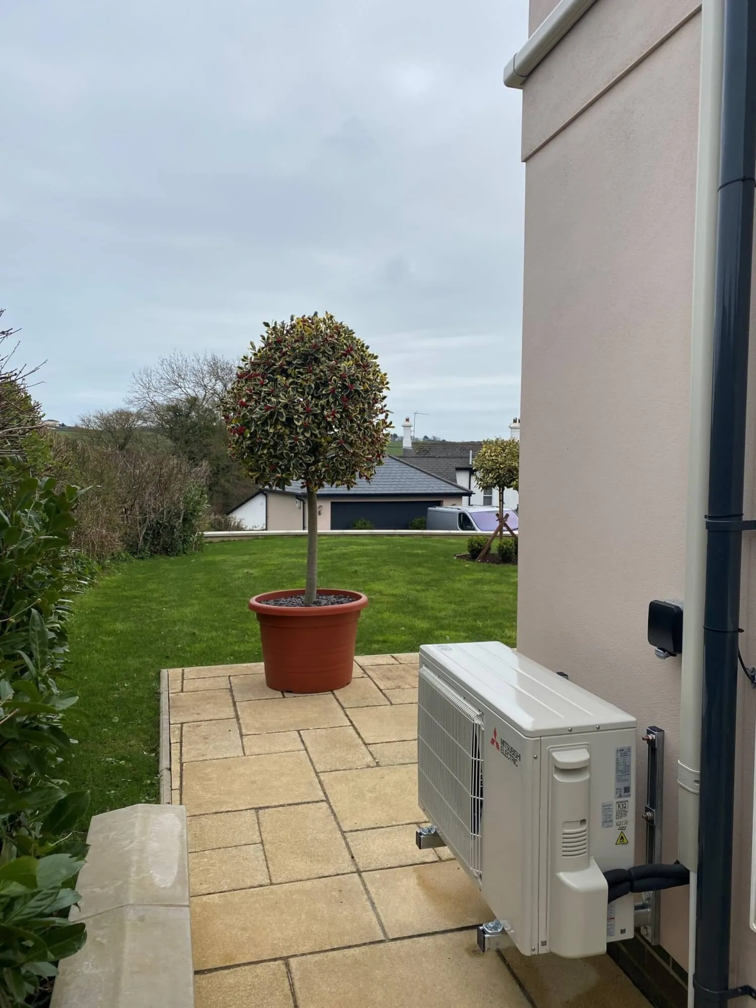 An air conditioner sitting on a patio next to a potted plant.