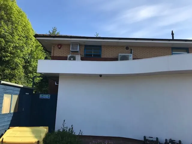 A white house with a yellow bench in front of it.