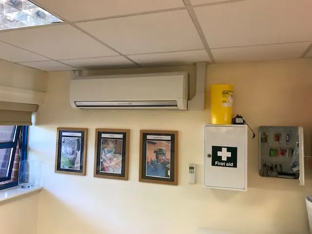 A room with a wall mounted air conditioner and pictures on the wall.