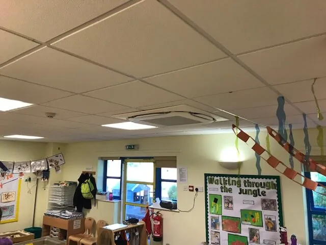 A classroom with a lot of clutter on the desks.