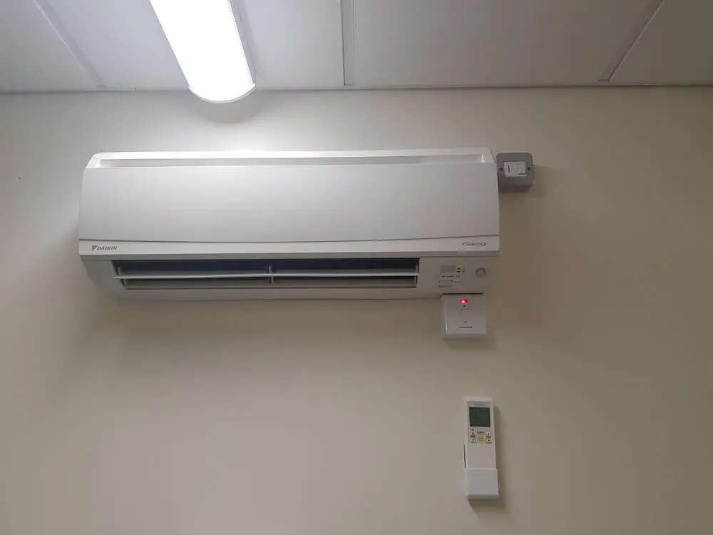 A white air conditioner sitting on top of a wall.