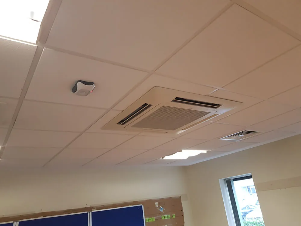 A room that has some kind of air conditioner on the ceiling.