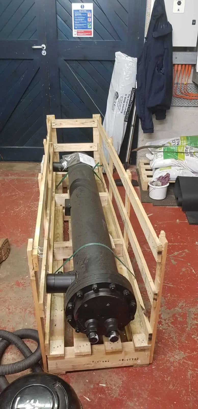 A wooden crate with a large black object inside of it.