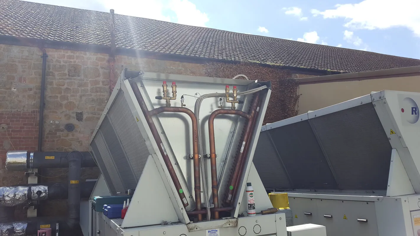 A large machine is parked in front of a brick building.